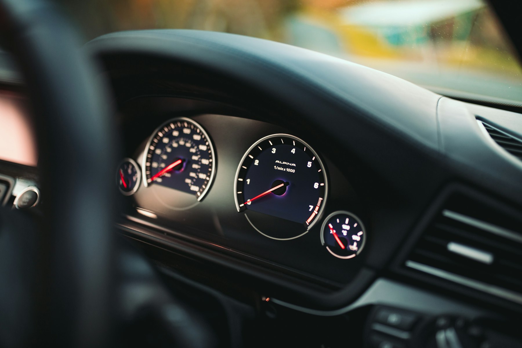 A close view of an illuminated instrument cluster behind a steering wheel. Illustrative photography — not a vehicle held, offered for sale, or priced by Automotive Car Brokers.