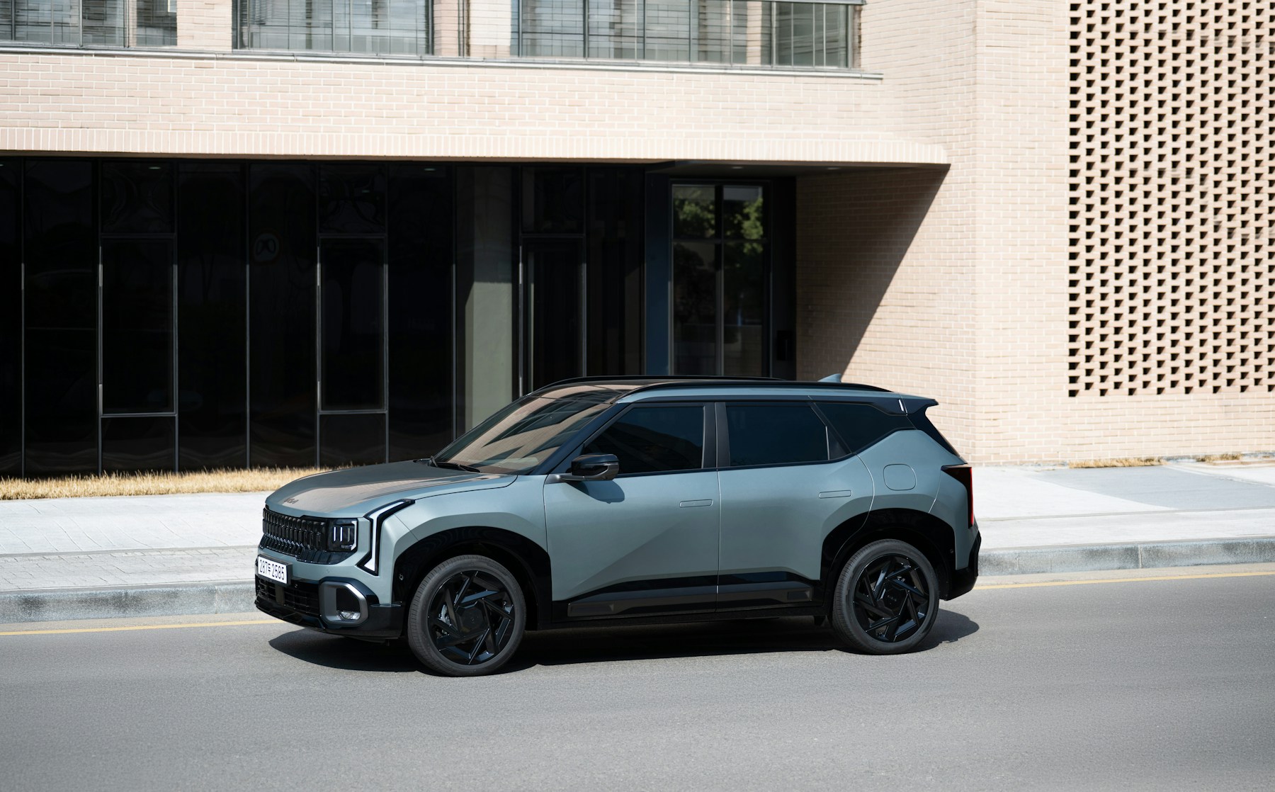 A gray compact SUV parked on a sunlit city street beside a plain modern building. Illustrative photography — not a vehicle held, offered for sale, or priced by Automotive Car Brokers.